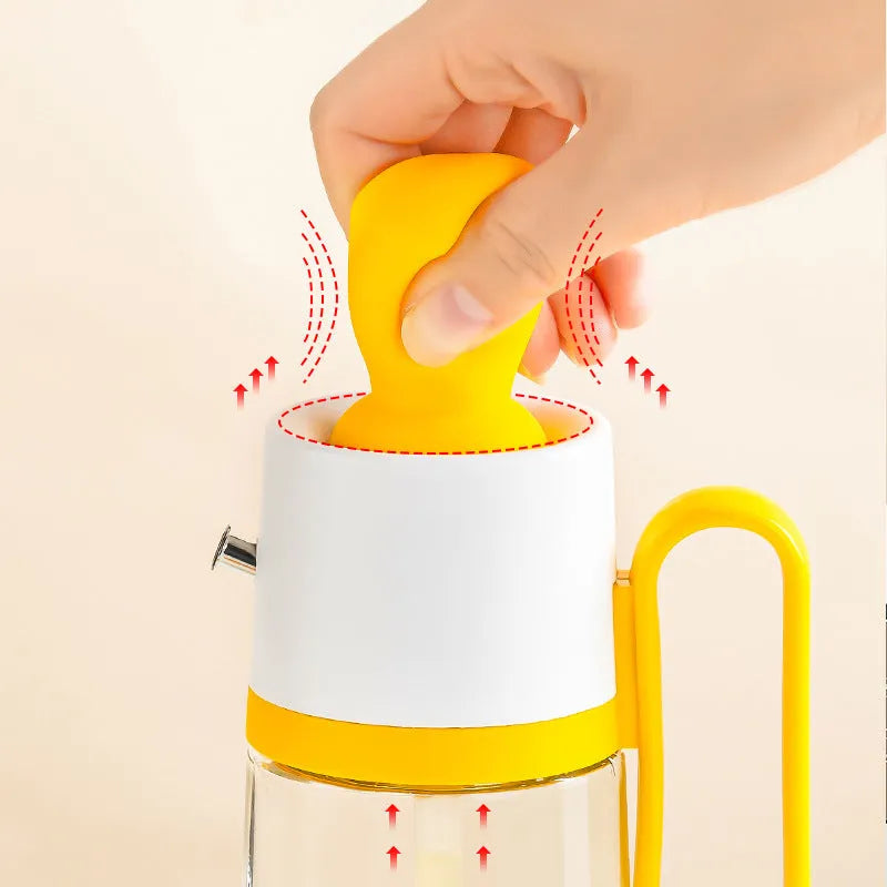 Yellow 2 in 1 oil dispenser with silicone brush next to glass bottle