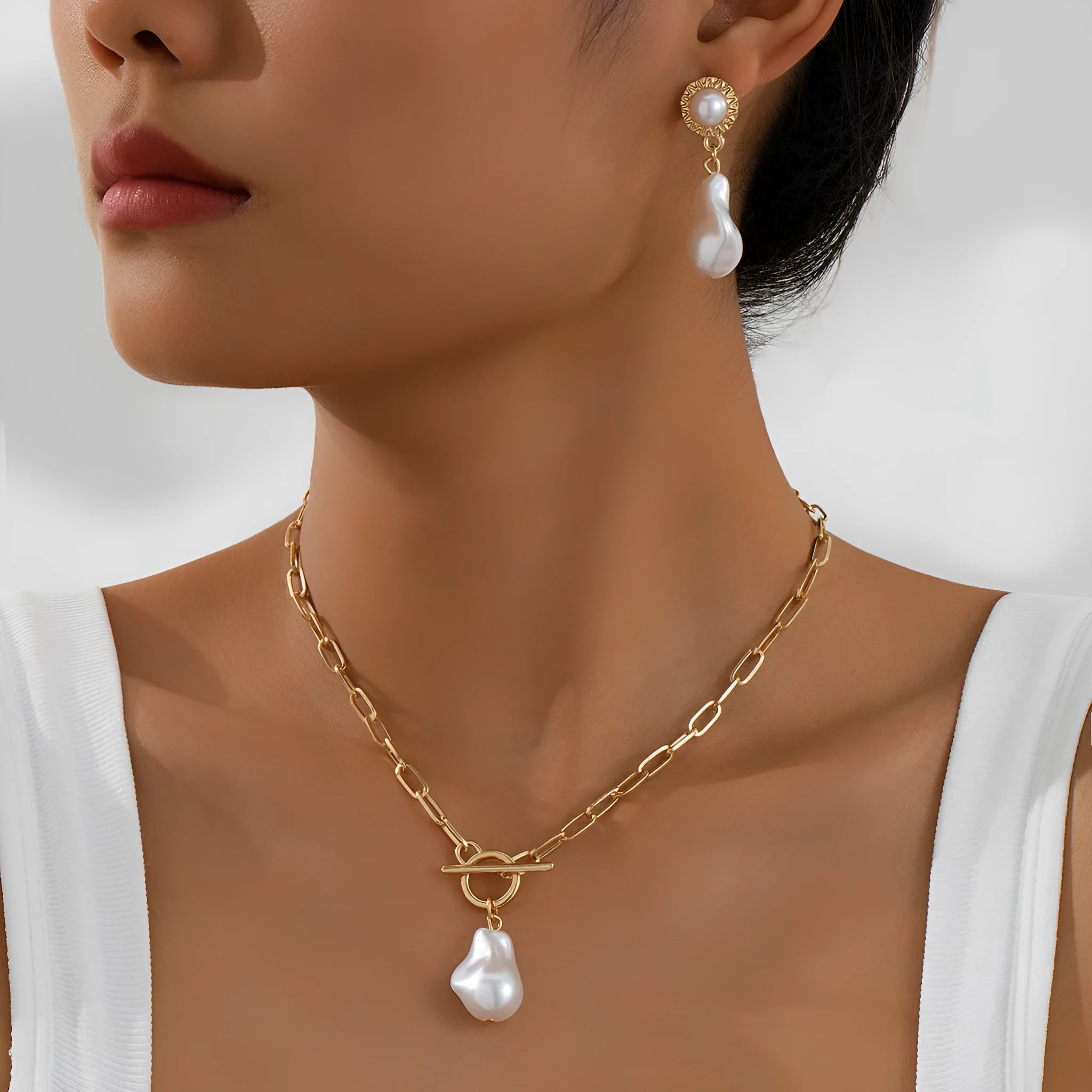 Gold baroque pearl pendant necklace and matching ear stud jewellery set on white background