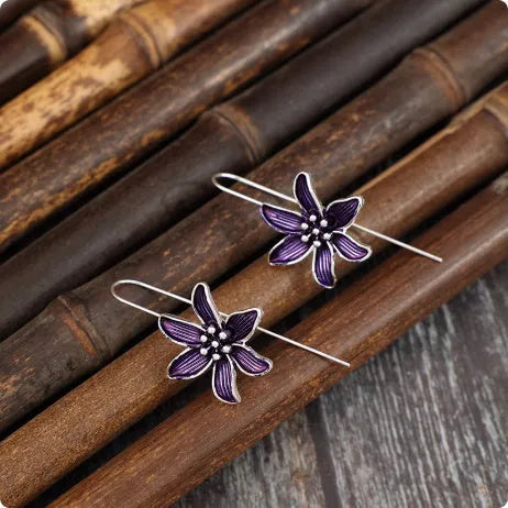 A pair of purple floral alloy earrings with a retro design on a white background.