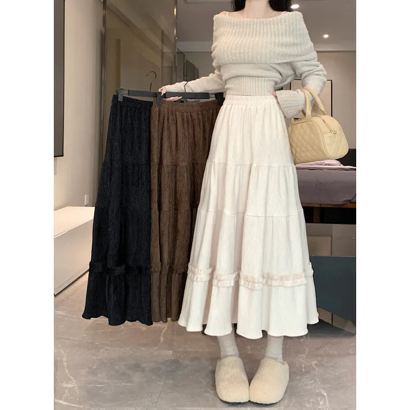 A woman modelling a beige corduroy midi A-line skirt with an elasticated waistband.