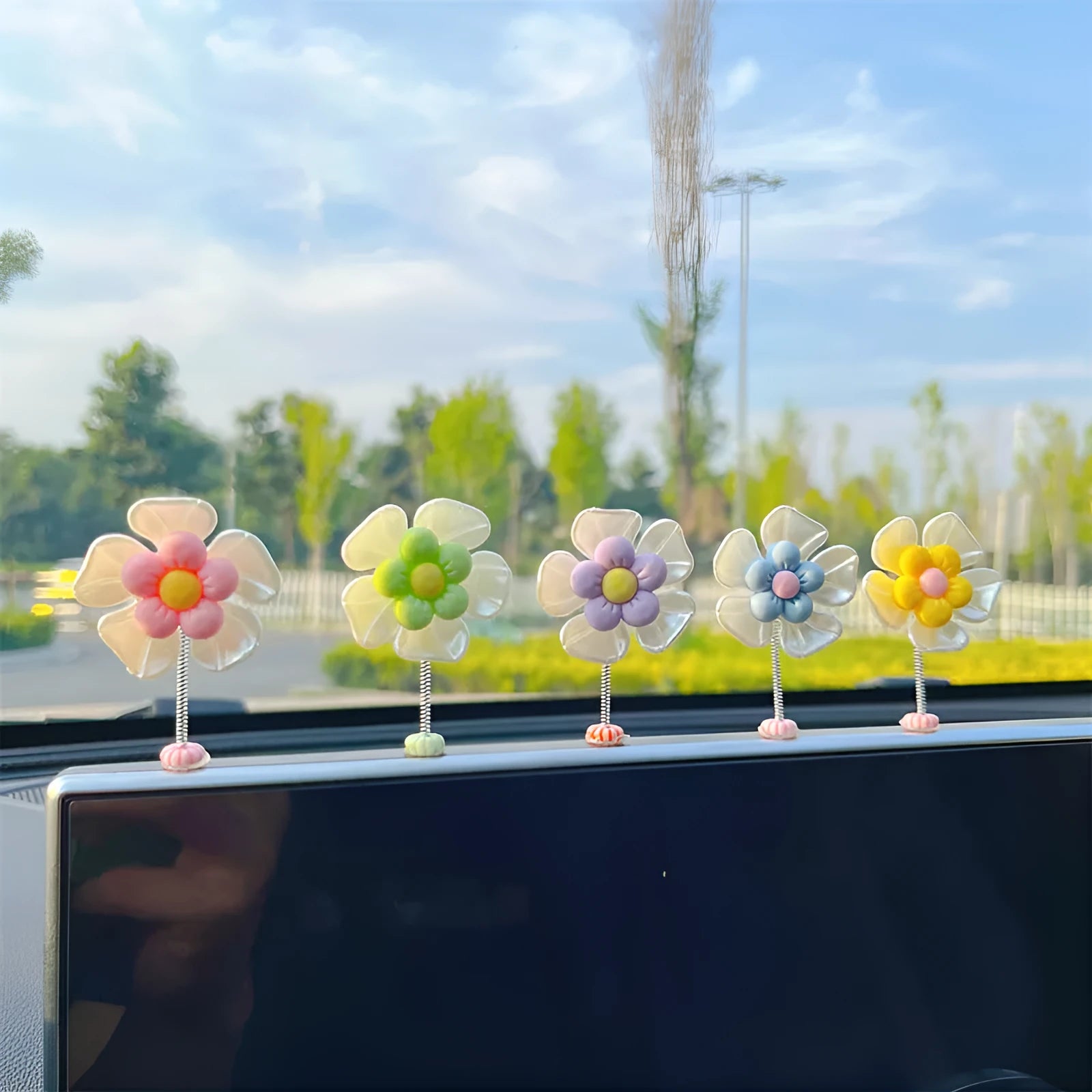 Small colourful plastic swing car decoration hanging from a rear-view mirror, showing blue, green, pink, purple, and yellow colour options.