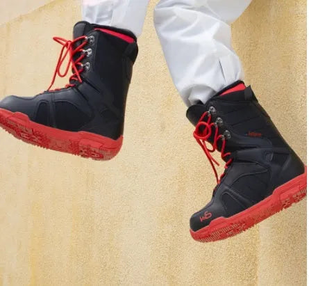Black men's ski boots with tie closure and rubber outsole on a snowy surface