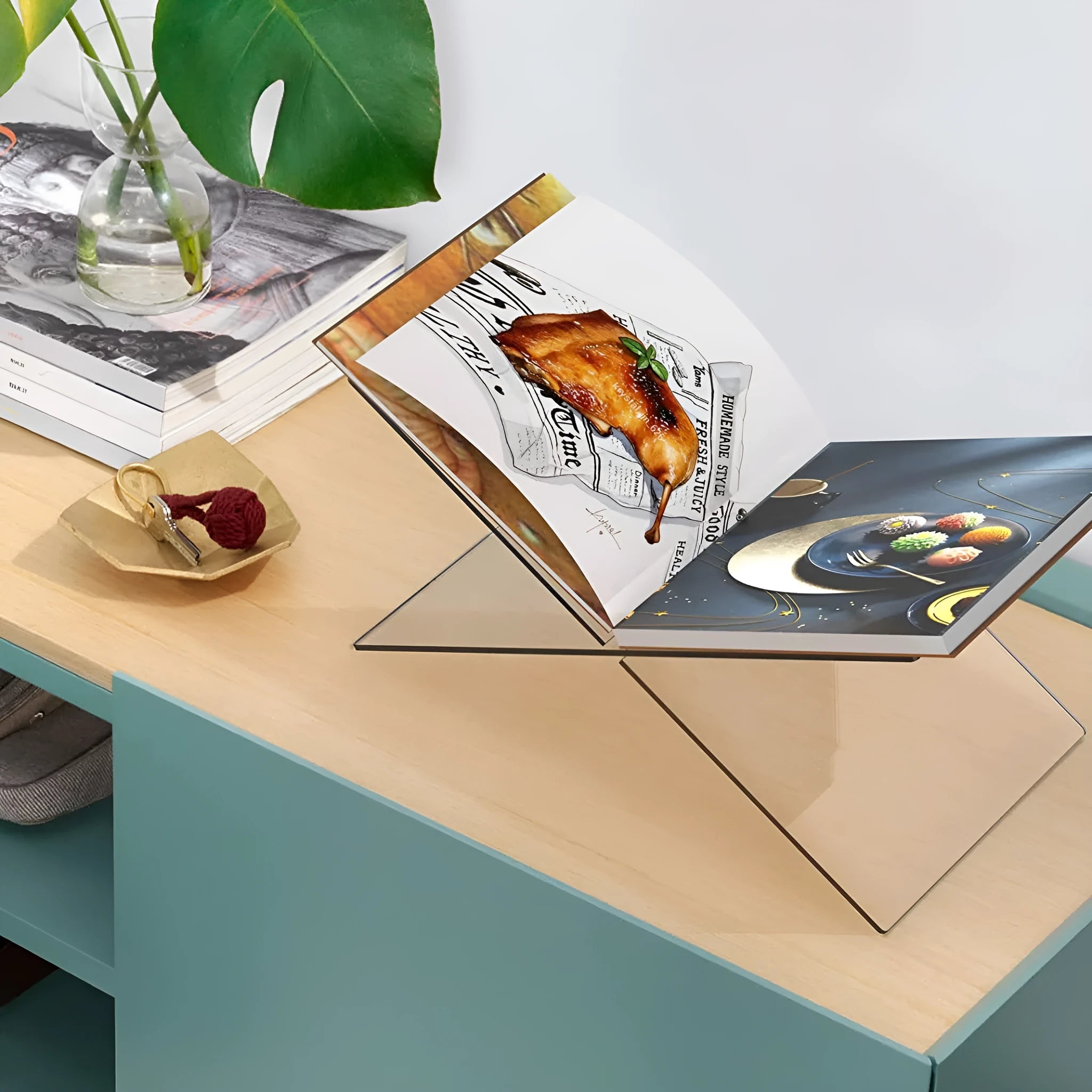 Clear acrylic X-shaped book display rack holding several upright books on a desk