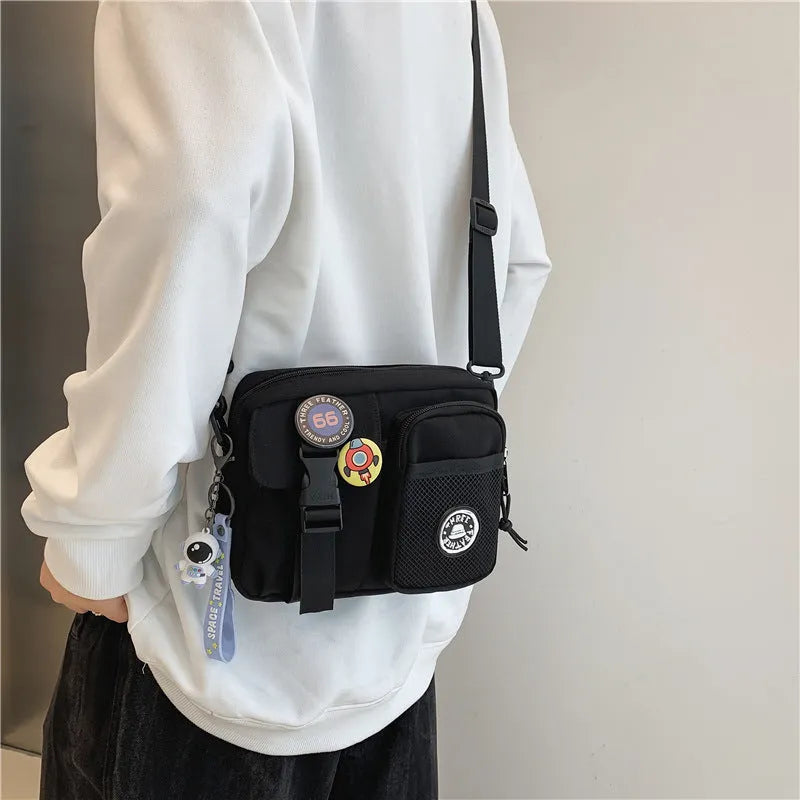 Casual nylon messenger bag for men and women, 22 x 6 x 17 cm, in black milky white grey or blue with two badge pendants