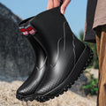 Men's black red PVC rain boot with round toe and plastic sole on a wet surface