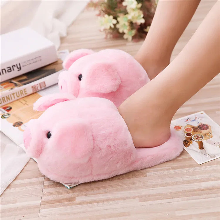 Pink pig-shaped plush house slippers with a short pile exterior, shown on a plain background.