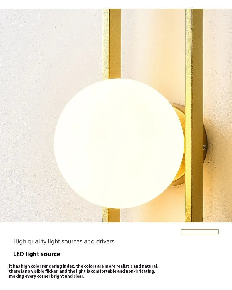 Modern minimalist wall lamp with black iron arm and clear glass shade, mounted on a plain wall.