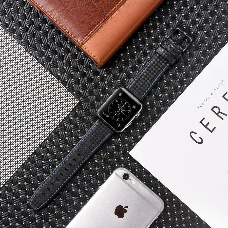 Leather and carbon fibre Apple Watch strap with red stitching next to a black PC case with carbon fibre pattern.