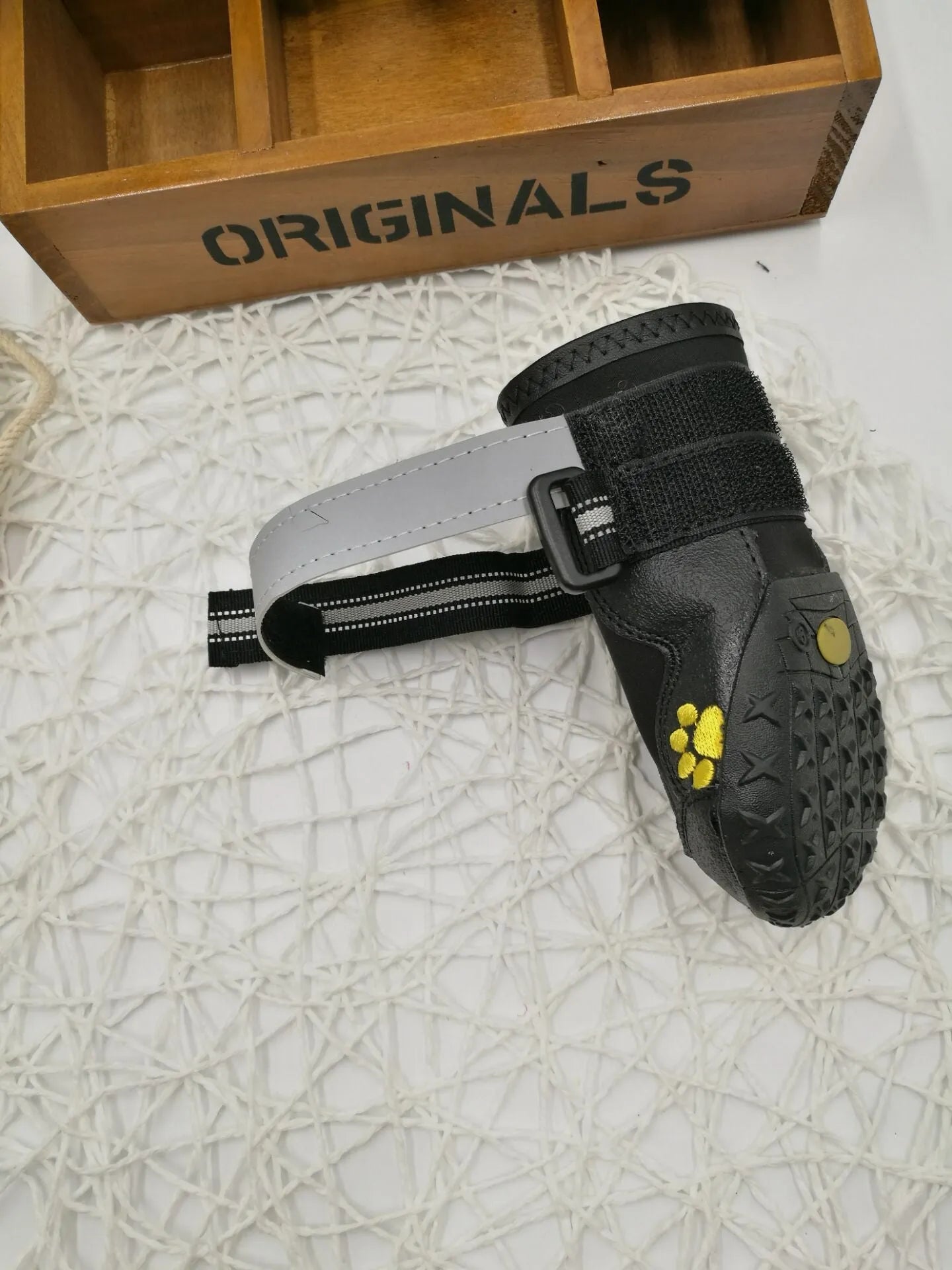 Black pet dog shoes with waterproof PVC sole and adjustable fuzzy belt on a light background