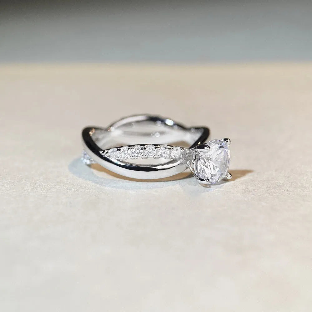 Geometric twisted silver band ring with a 1 carat round moissanite stone in a four-claw setting.