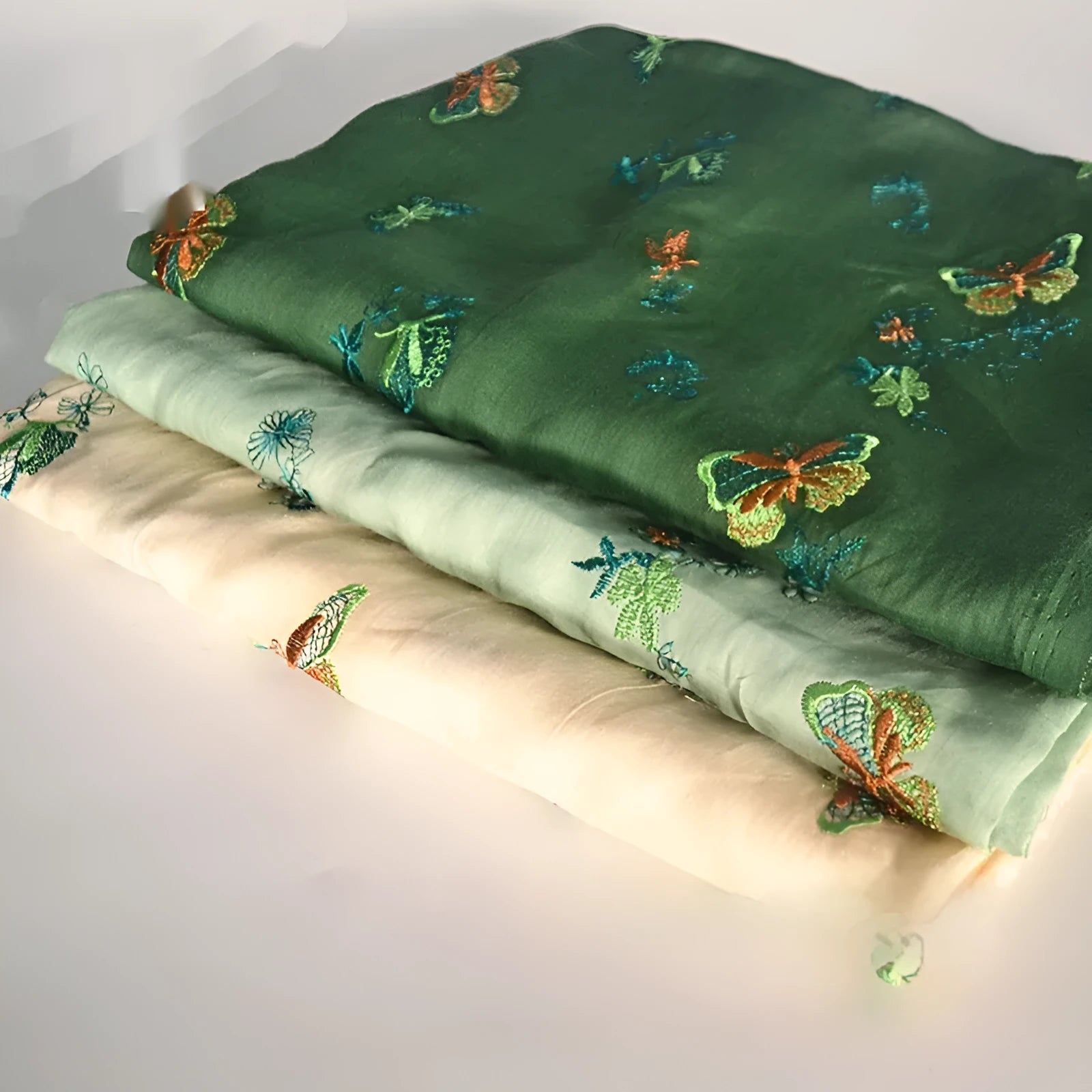 Pure ramie embroidery cloth fabric on a roll showing beige, dark green, and grass green colour options.
