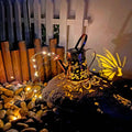 Solar-powered iron garden lamp with tapered butterfly design and warm white LED light.