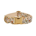 Small white flower pet dog collar set with matching vest, leash, bow, and accessories on a cloth background.