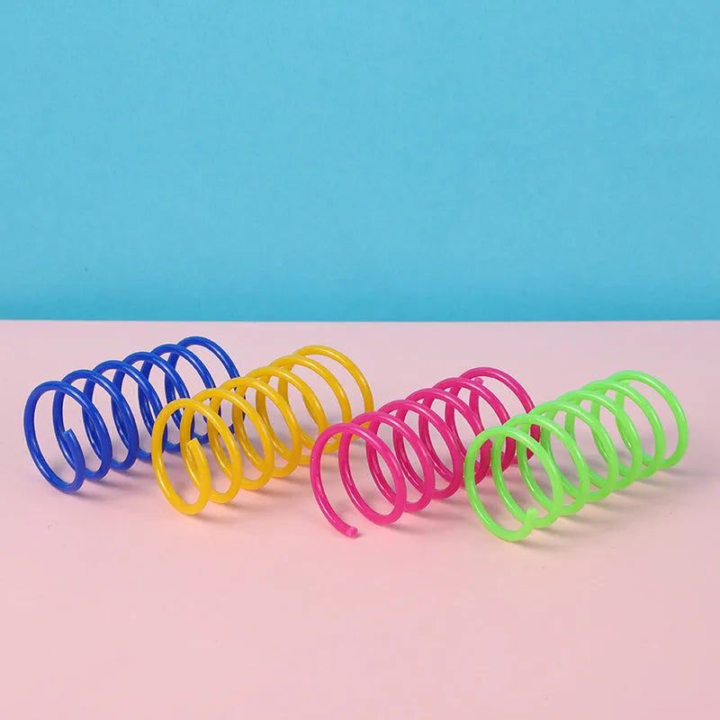 Colourful plastic coil spring toys for cats on a wooden floor.