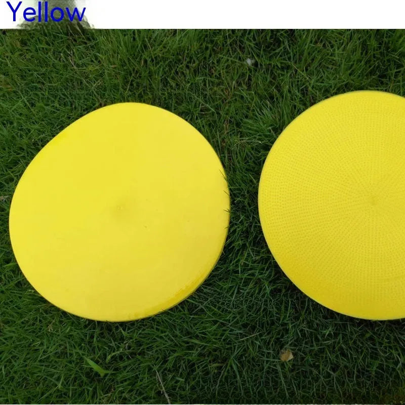Soft yellow TPE football training target pad flat on grass, 23cm diameter.