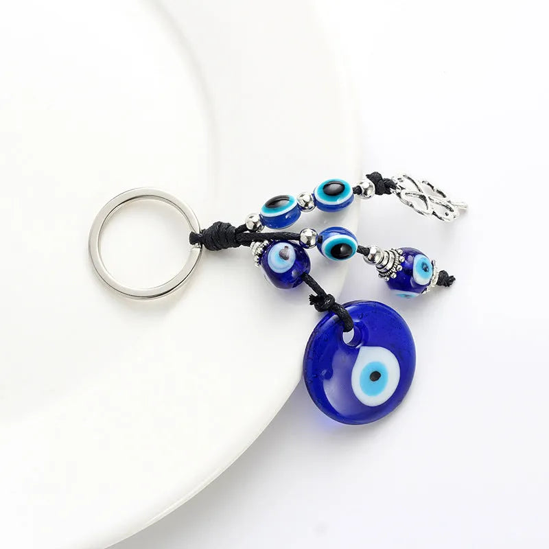 Blue metal eye of evil keychain 4cm pendant with plant-inspired design on grey background