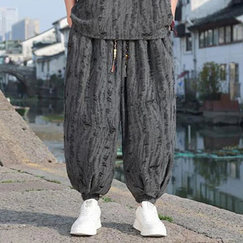 Man wearing a thin grey short-sleeved knitwear top and matching cropped trousers, a casual two-piece suit.
