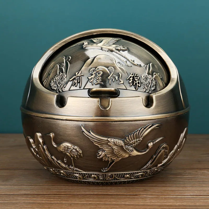 Bronze and red copper alloy decorative ashtray with smoke-extinguishing slot on a table.