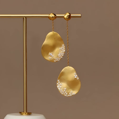 Asymmetric floral earrings with zircon stones in gold or silver finish.