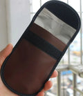 Black microfiber Faraday cage pouch for blocking car key and RFID card signals on a table.