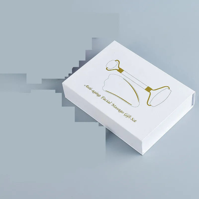 White jade double-headed facial roller and gua sha scraping tool set on a storage board.