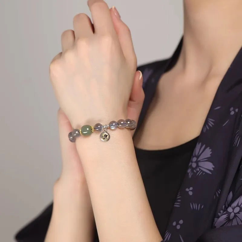Moonstone bracelet with 8mm beads and a silver Guanyin mouse zodiac charm on a black background.