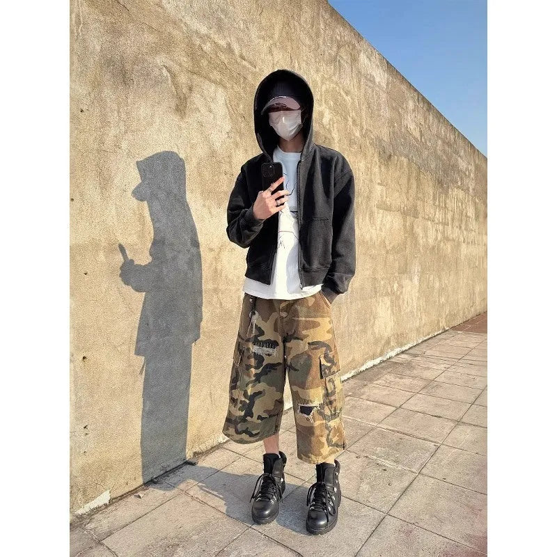 Men's loose-fit camouflage cropped jeans with ripped details and patches on a straight leg.