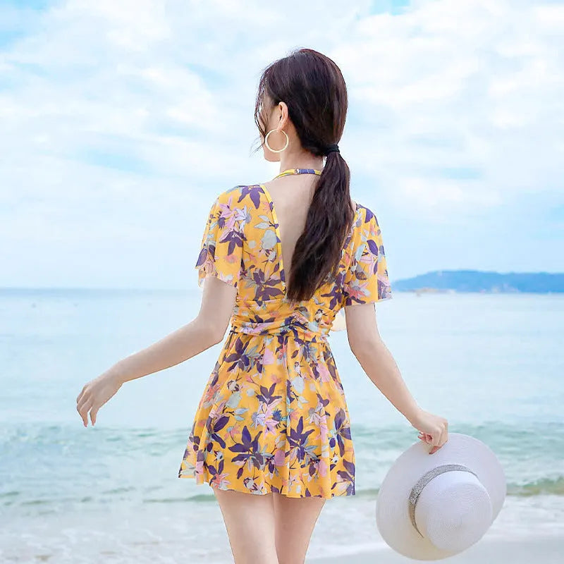 Yellow floral print women's one-piece swimsuit with skirted design on mannequin.