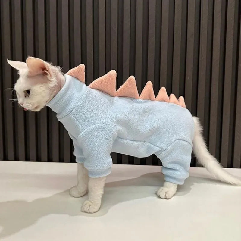 Green fleece dinosaur costume on a hairless Sphynx cat, showing tail and spine details.