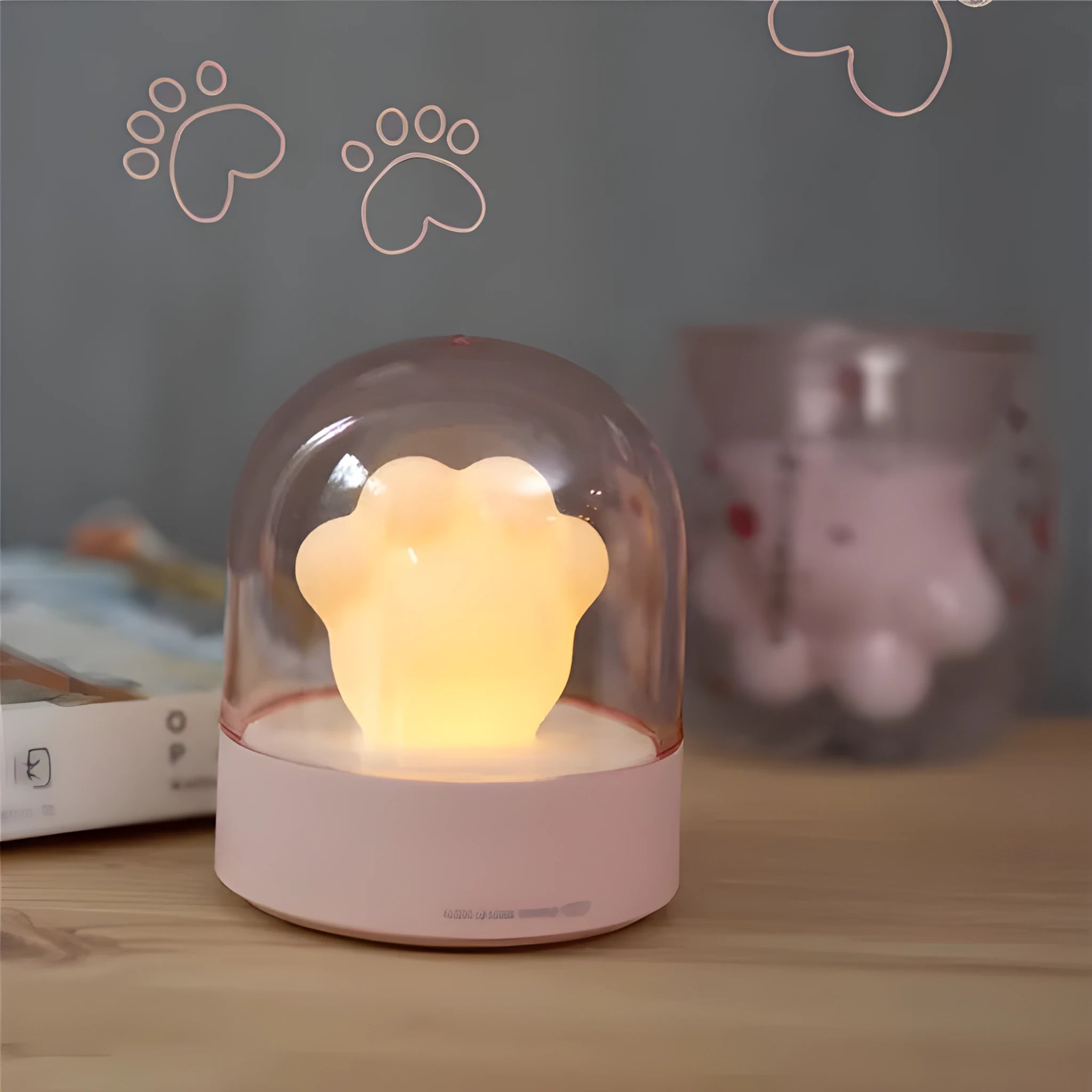 Pink cat paw shaped USB rechargeable night light with soft glow on a desk.