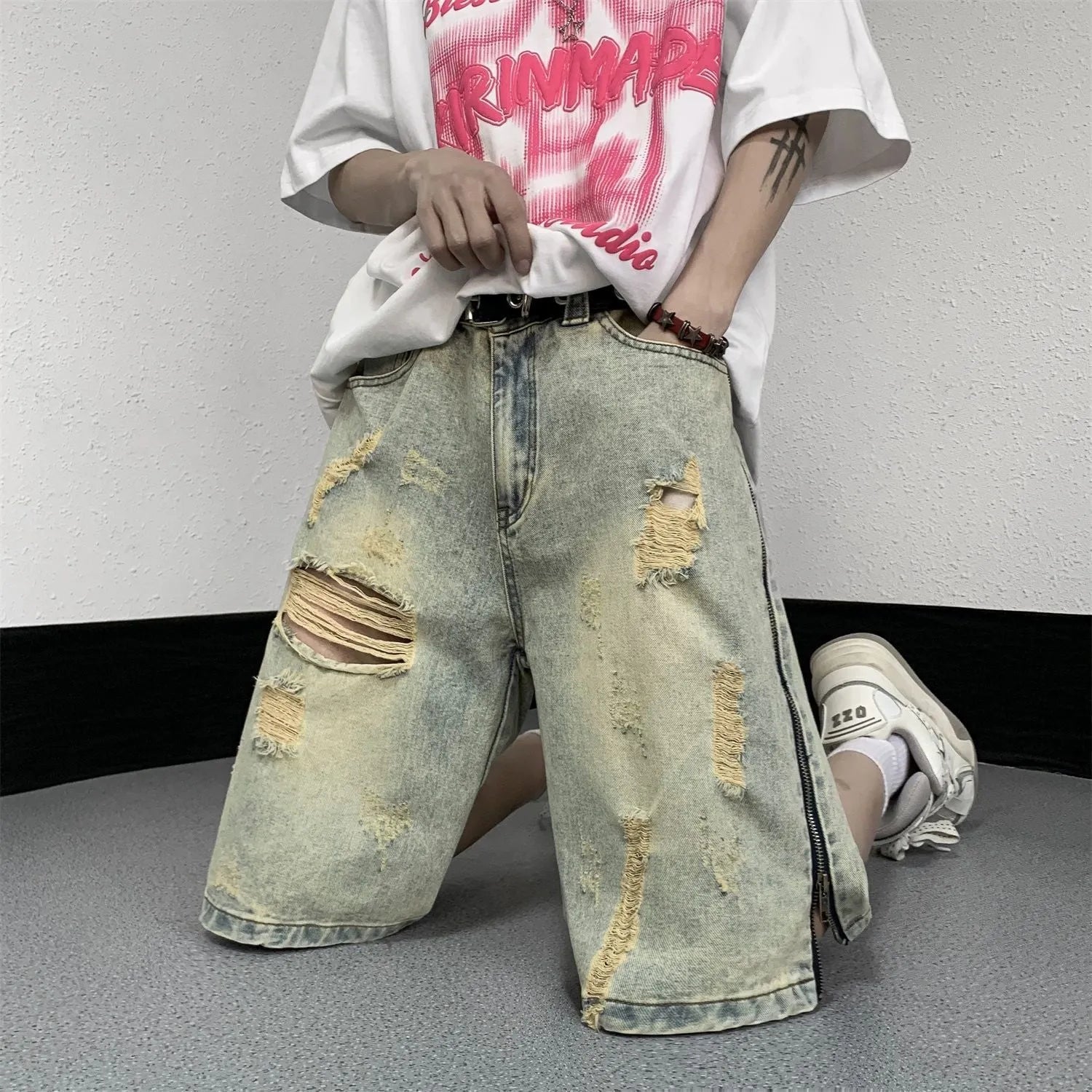 Men's blue denim shorts with yellow mud finish, ripped details, cardigan buttons, and a straight leg opening.