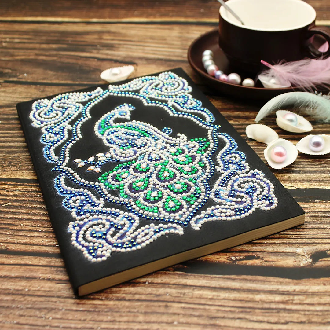 Black A5 diamond painting notebook open, showing journal pages alongside shaped and bright sparkling drills.