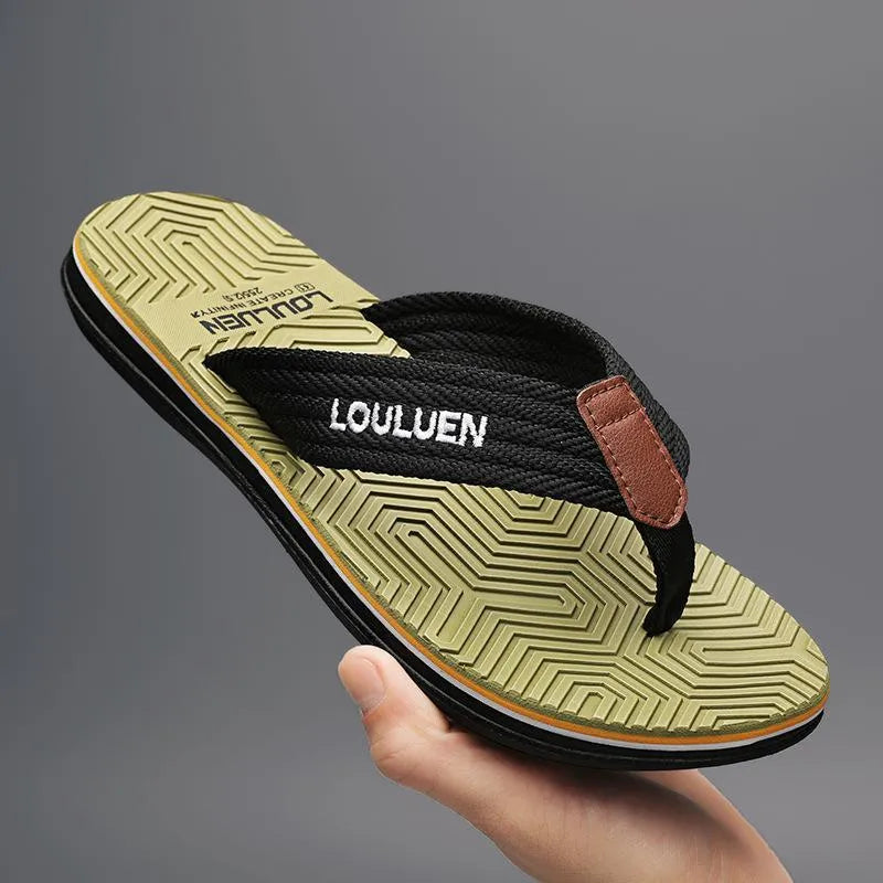 Men's black flip flops with textured non-slip sole on a beach background.
