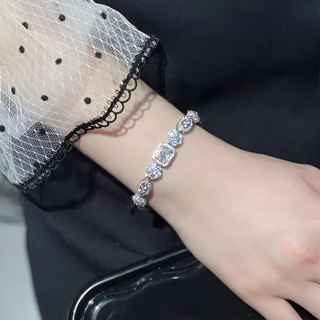 Close-up of a women's geometric silver bracelet with inlaid zircon stones on a wrist, showing adjustable chain.