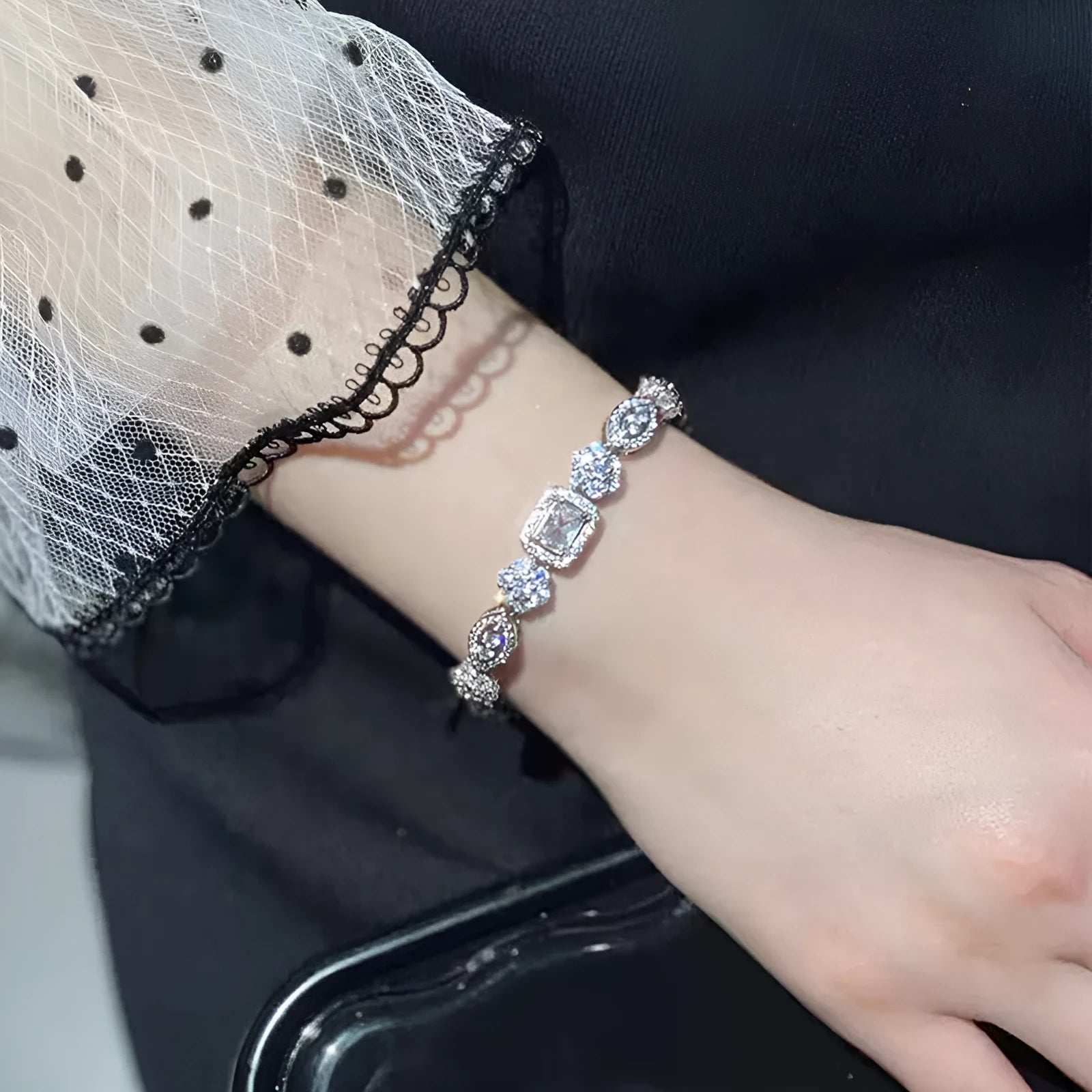 Close-up of a women's geometric silver bracelet with inlaid zircon stones on a wrist, showing adjustable chain.