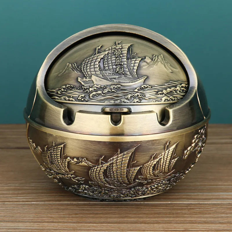 Bronze and red copper alloy decorative ashtray with smoke-extinguishing slot on a table.