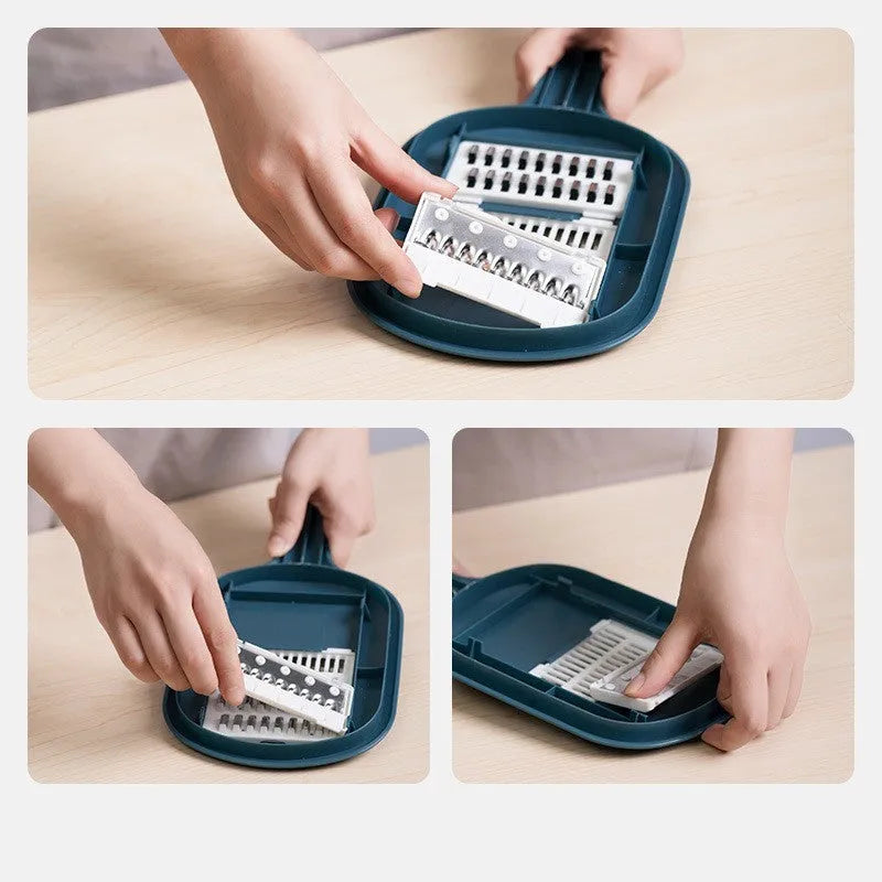 Dark blue vegetable cutter with four stainless steel blades, a hand guard, and a drain basket on a kitchen counter.