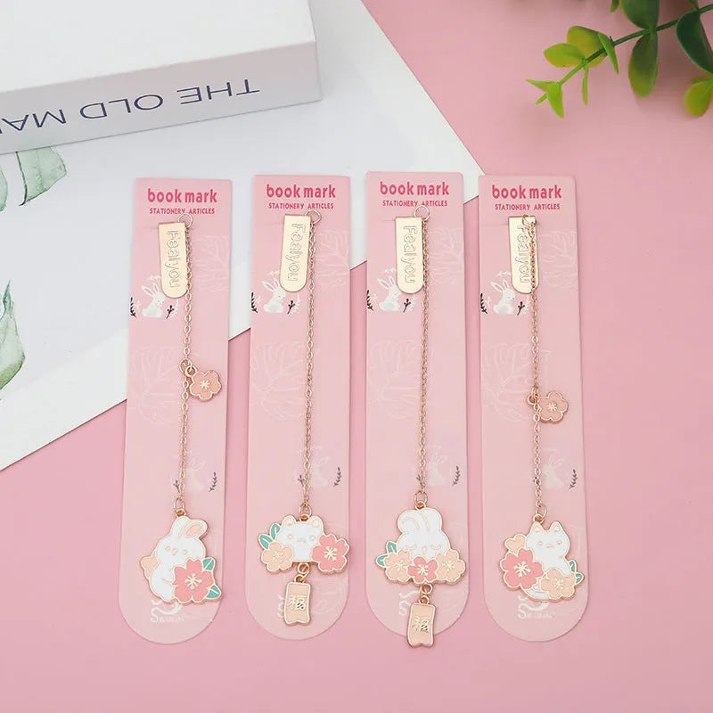 Small metal bookmark pendant with cherry blossom and cartoon cat or rabbit design.