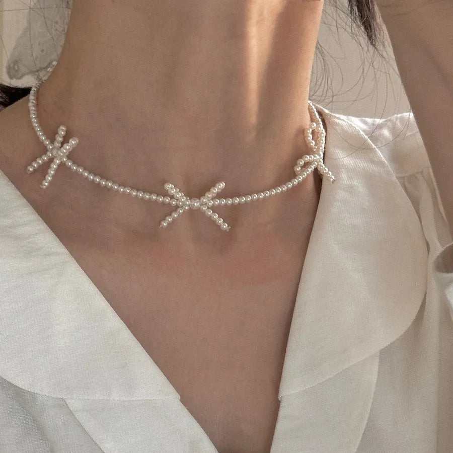 Women's white imitation pearl necklace with sweet bow design and geometric shapes on adjustable chain