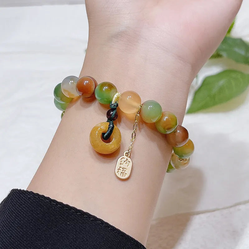 Yellow peacock agate and topaz beaded bracelet with a metal safety chain and peace buckle clasp.