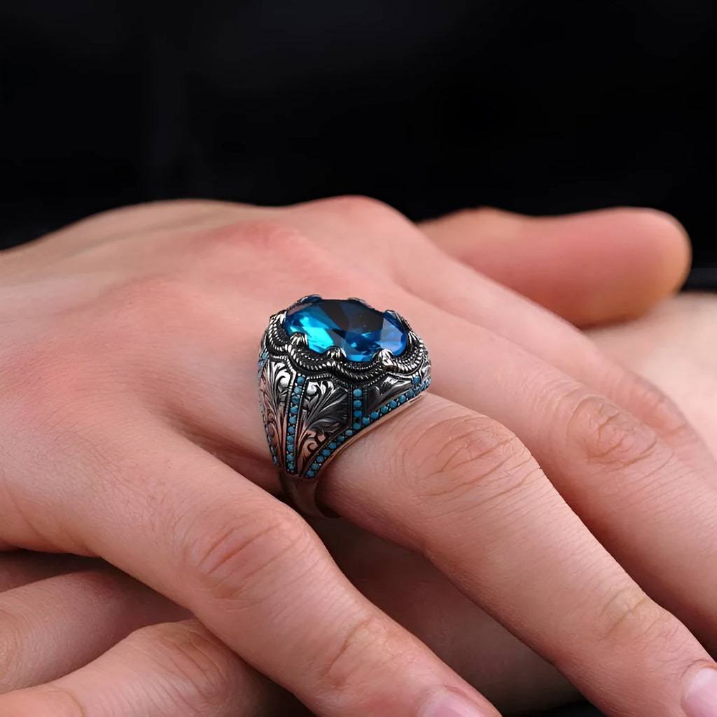 Geometric antique silver unisex ring with a central blue zircon stone on a finger.
