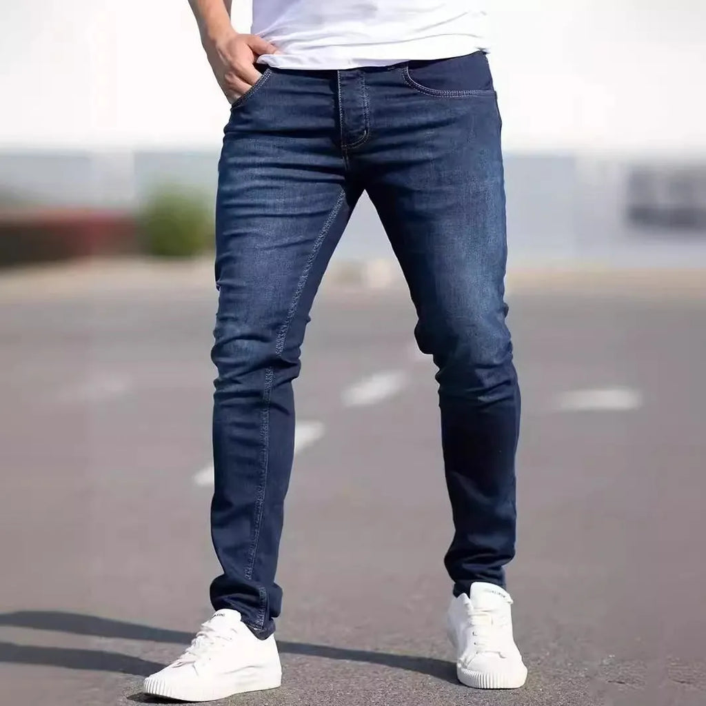 Men's dark blue skinny fit cotton jeans with a mid-rise waist and zipper fly on a plain background.