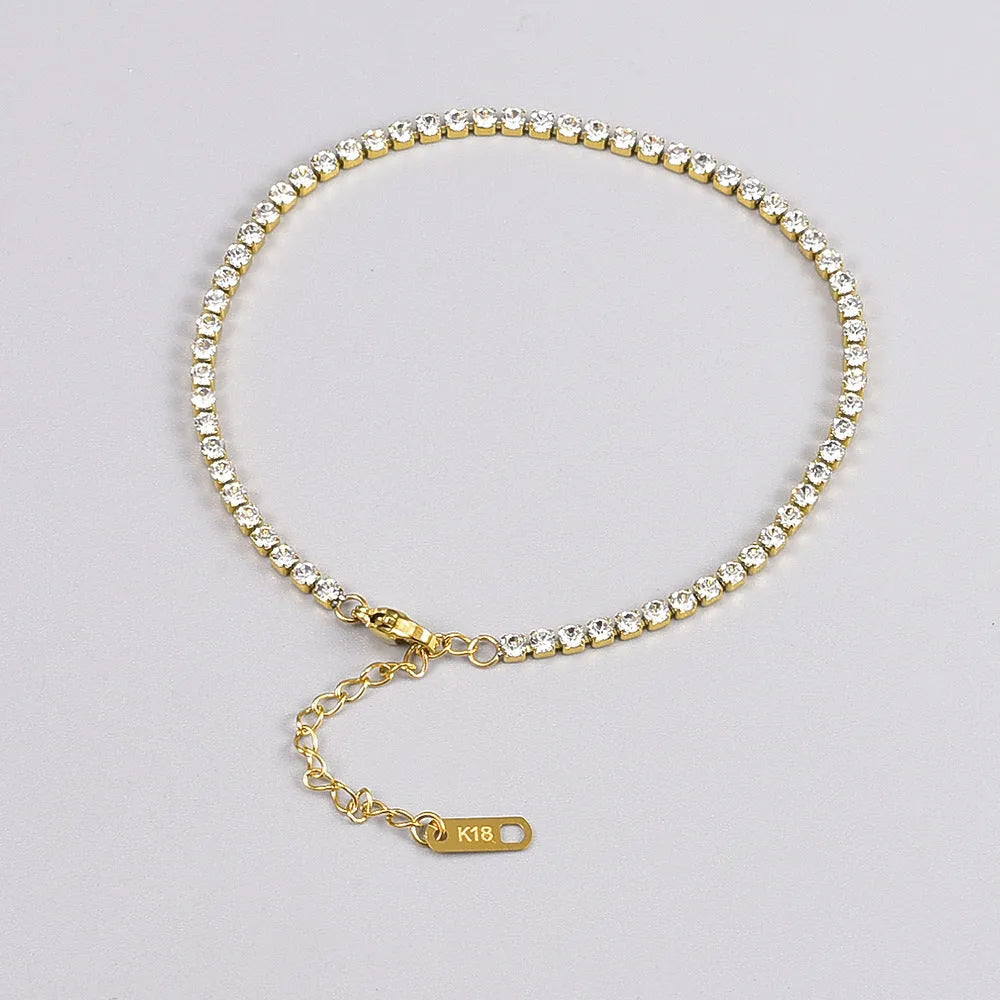 Gold titanium steel anklet with small fruit-shaped pendant and adjustable tail chain on bare ankle