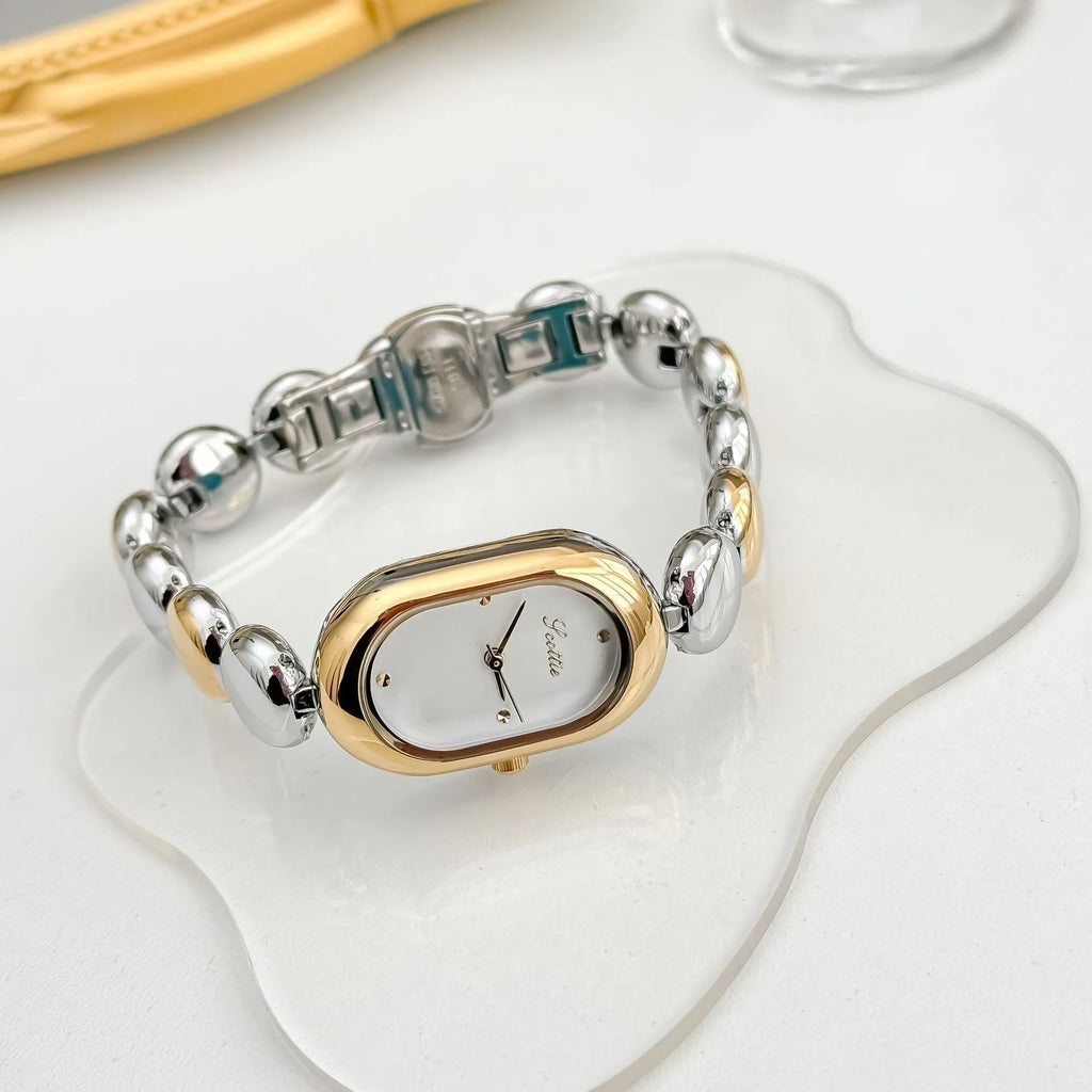 Oval women's fashion watch on wrist showing 9mm thick case, available in black gold, platinum and other colours.
