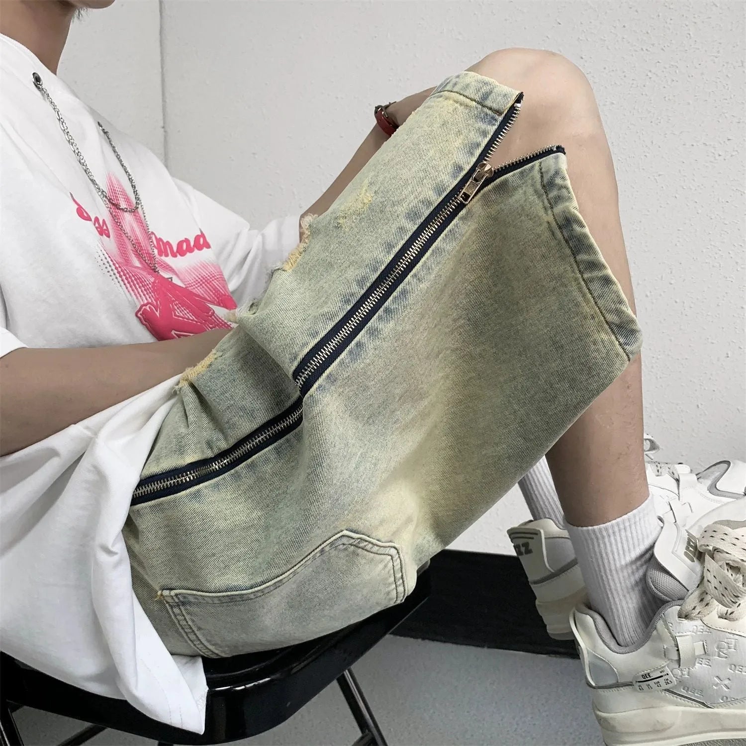 Men's blue denim shorts with yellow mud finish, ripped details, cardigan buttons, and a straight leg opening.