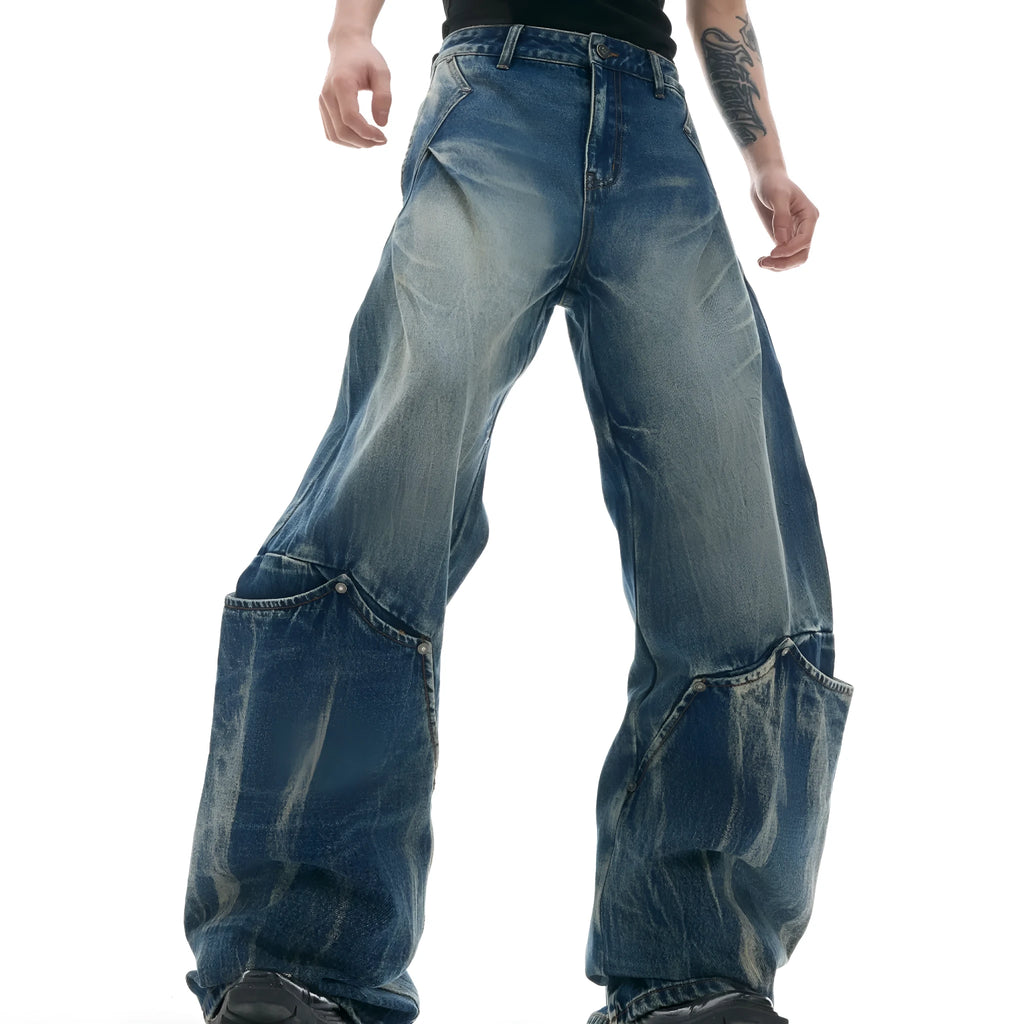 Man wearing verdant blue loose-fit retro jeans with a curved knife washed pattern on the legs.