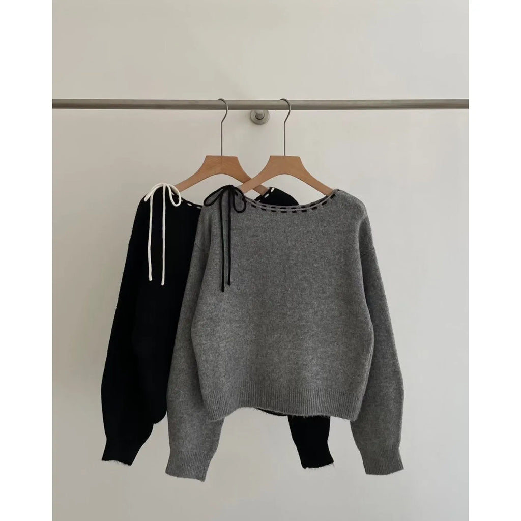 A loose-fitting black women's knitted pullover on a hanger.