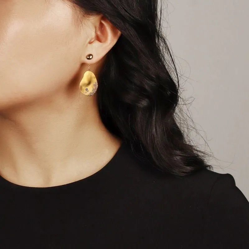 Asymmetric floral earrings with zircon stones in gold or silver finish.