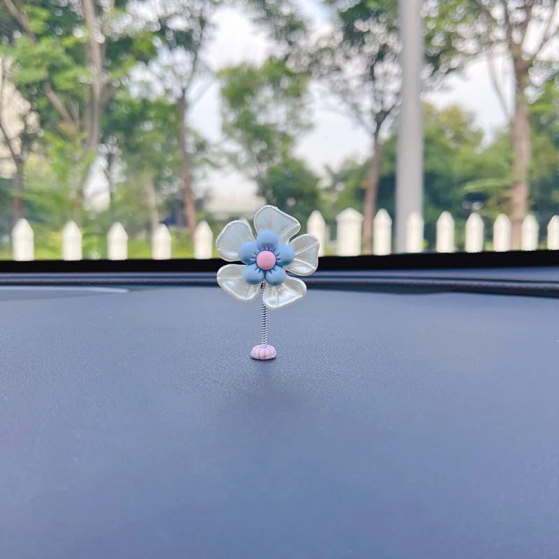 Small colourful plastic swing car decoration hanging from a rear-view mirror, showing blue, green, pink, purple, and yellow colour options.