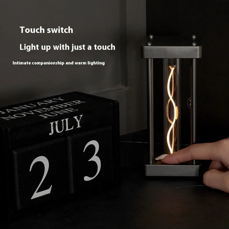 Metallic gray acrylic square night lamp with curved wire on a desk